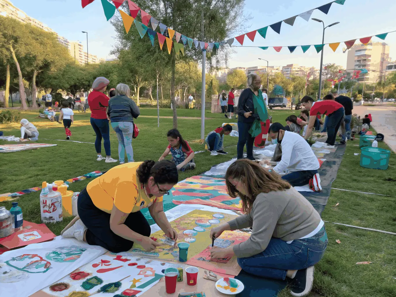 A photograph capturing a community outreach event organized by LA COUPE D'OR THEATRE DE ROCHEFORT, showing volunteers and participants engaging in an interactive art activity in a public space.